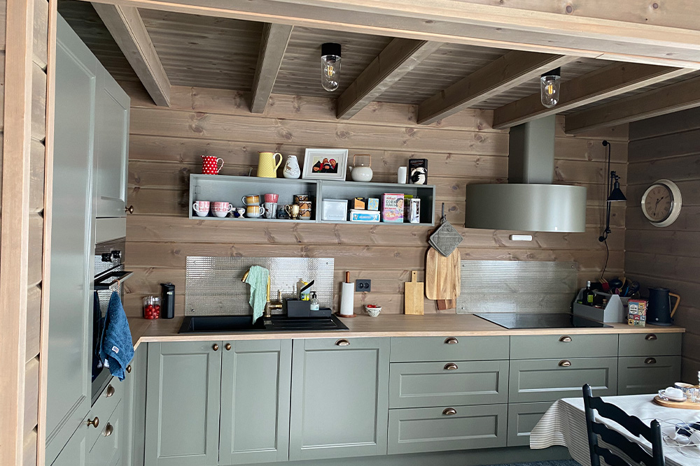Bilde av hyttekjøkken med drivvedgrå glattpanel og østerdalspanel. Finalist nummer 2 hytteprisen 2022.