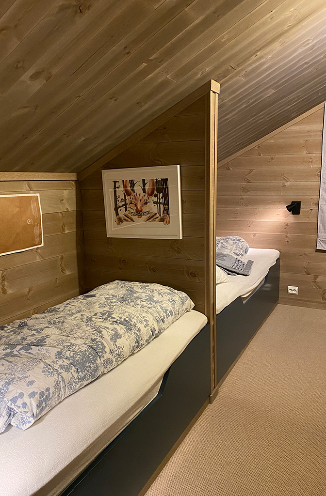 Bilde av soverom på hytta med drivvedgrå glattpanel og østerdalspanel. Finalist nummer 2 hytteprisen 2022.