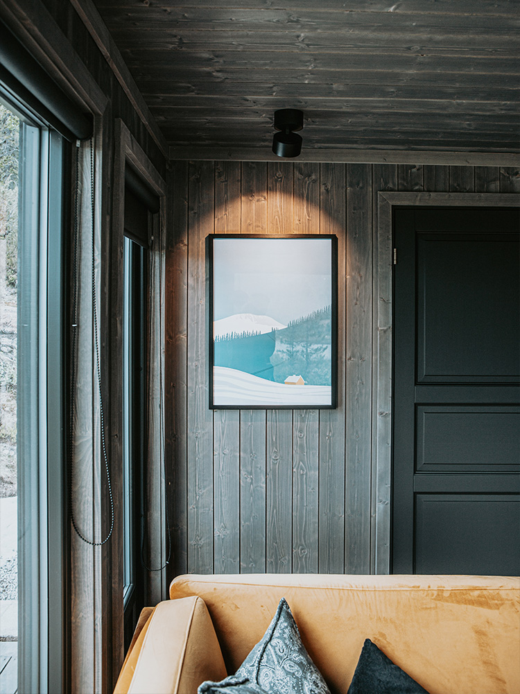 Bilde av hytte som vant hytteprisen 2021. Bilde av Mørkne granpanel i stuen fra interiørkolleksjonen NORD.
