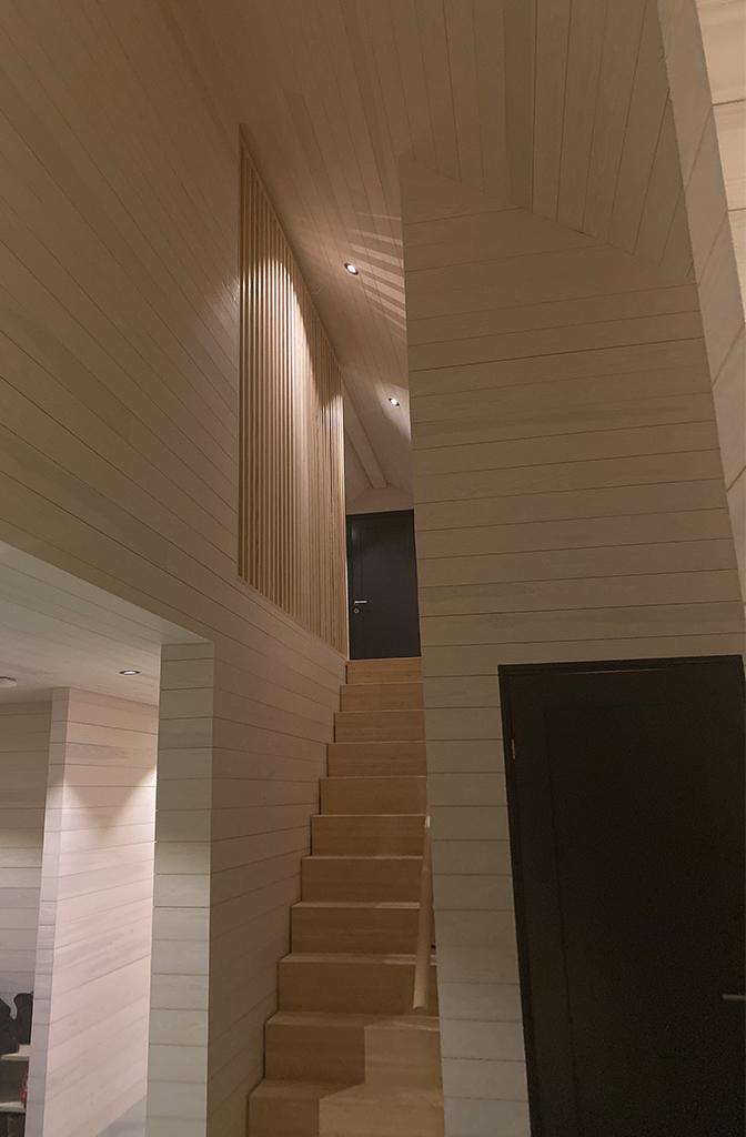 Bilde av gang med trapp hos finalist nummer 1 i hytteprisen 2022. Hvitlasert kvistfritt panel i hele hytta.