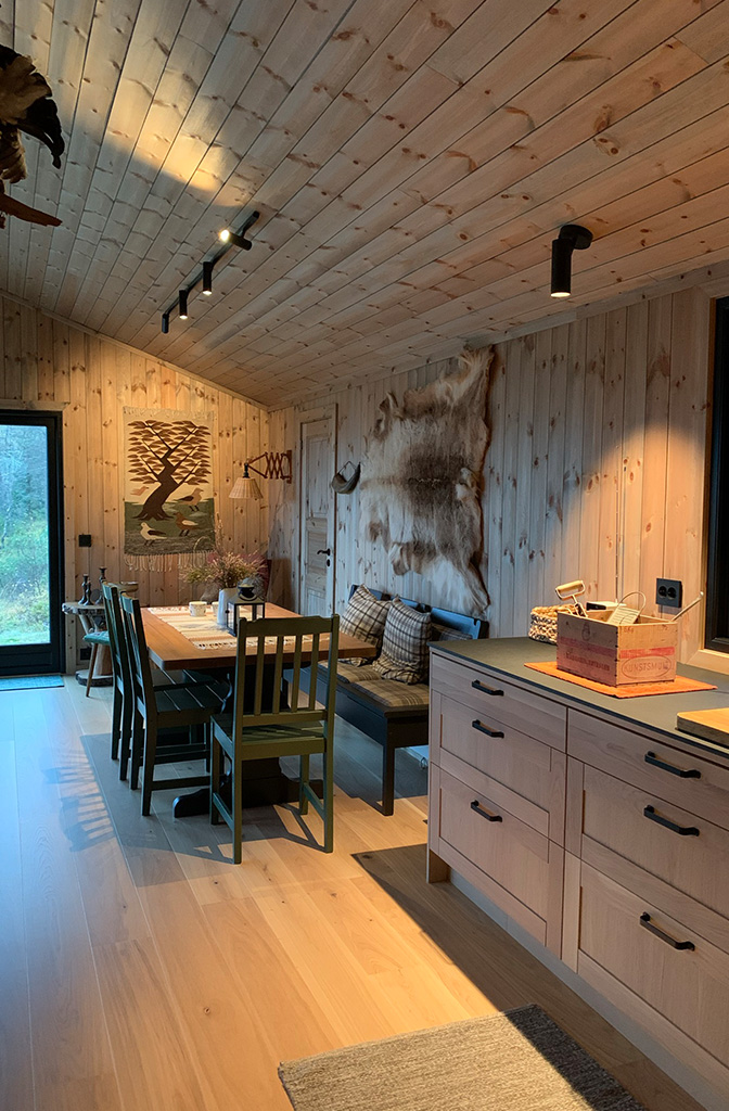 Bilde av kombinert stue og kjøkken på hytta. Nytt panel og nye vinduer på hytta. Finalist numer 5 hytteprisen 2022.
