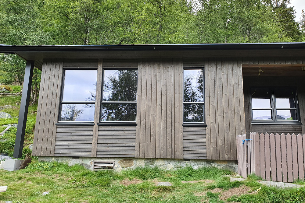 Bilde av hyttefinalist nummer 9 i hytteprisen 2022. Mørk og trendy hytte som originalt er fra 50-tallet.
